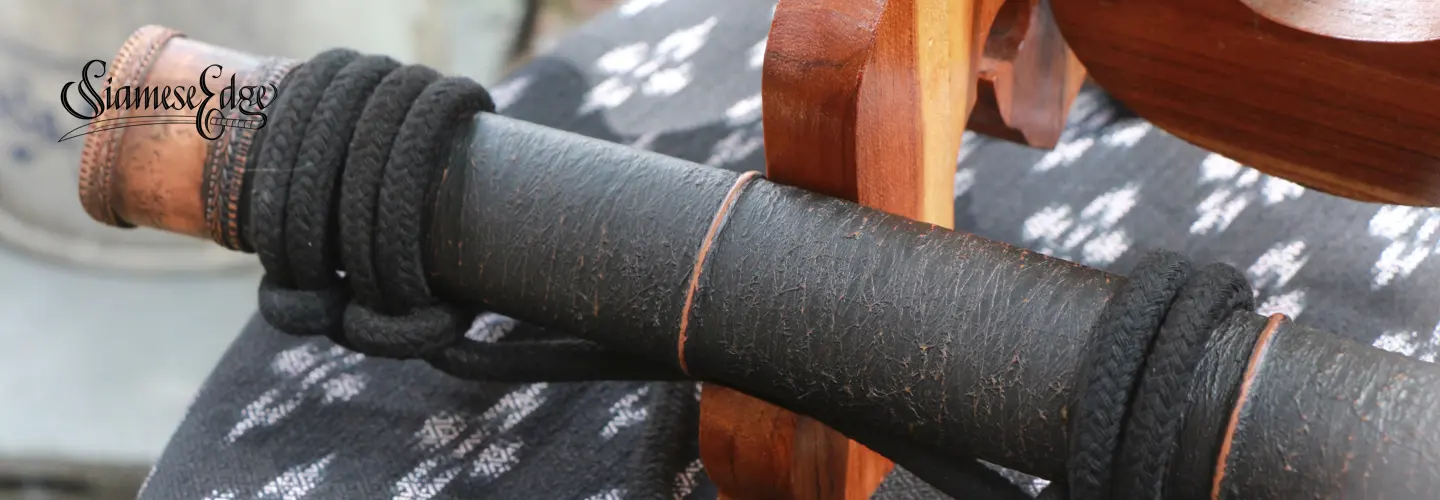 The black textured scabbard with copper bands and black braided carry rope