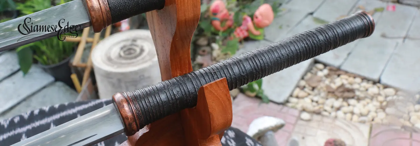 The cord-wrapped grip with copper hilt ring and pommel cap, on its stand