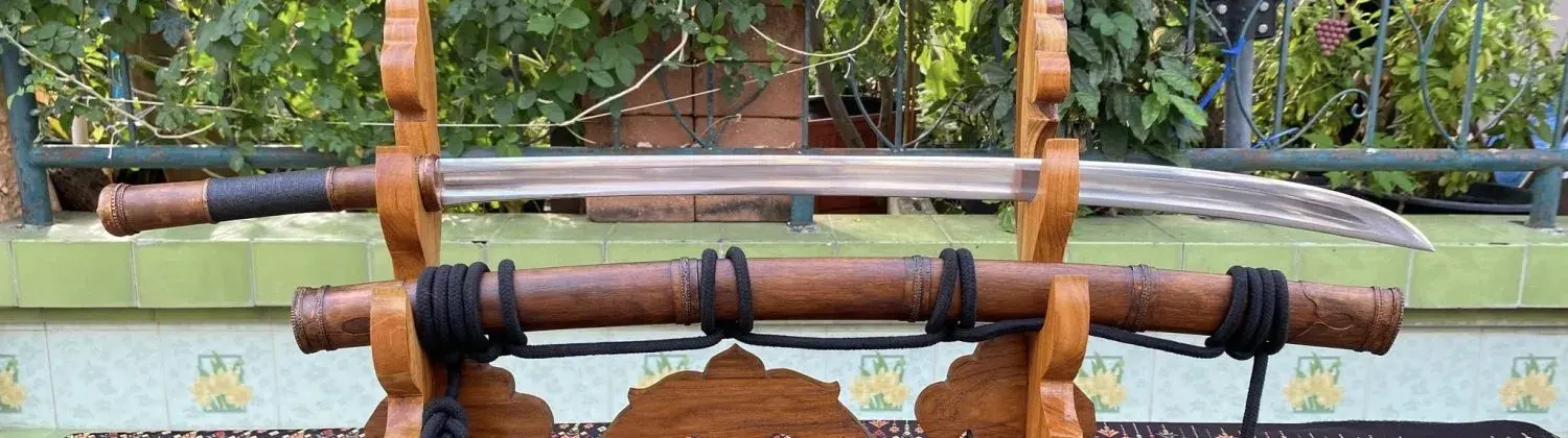 Type #2, Mindan style, with the oval Type E handle on a stand, black rope, garden behind