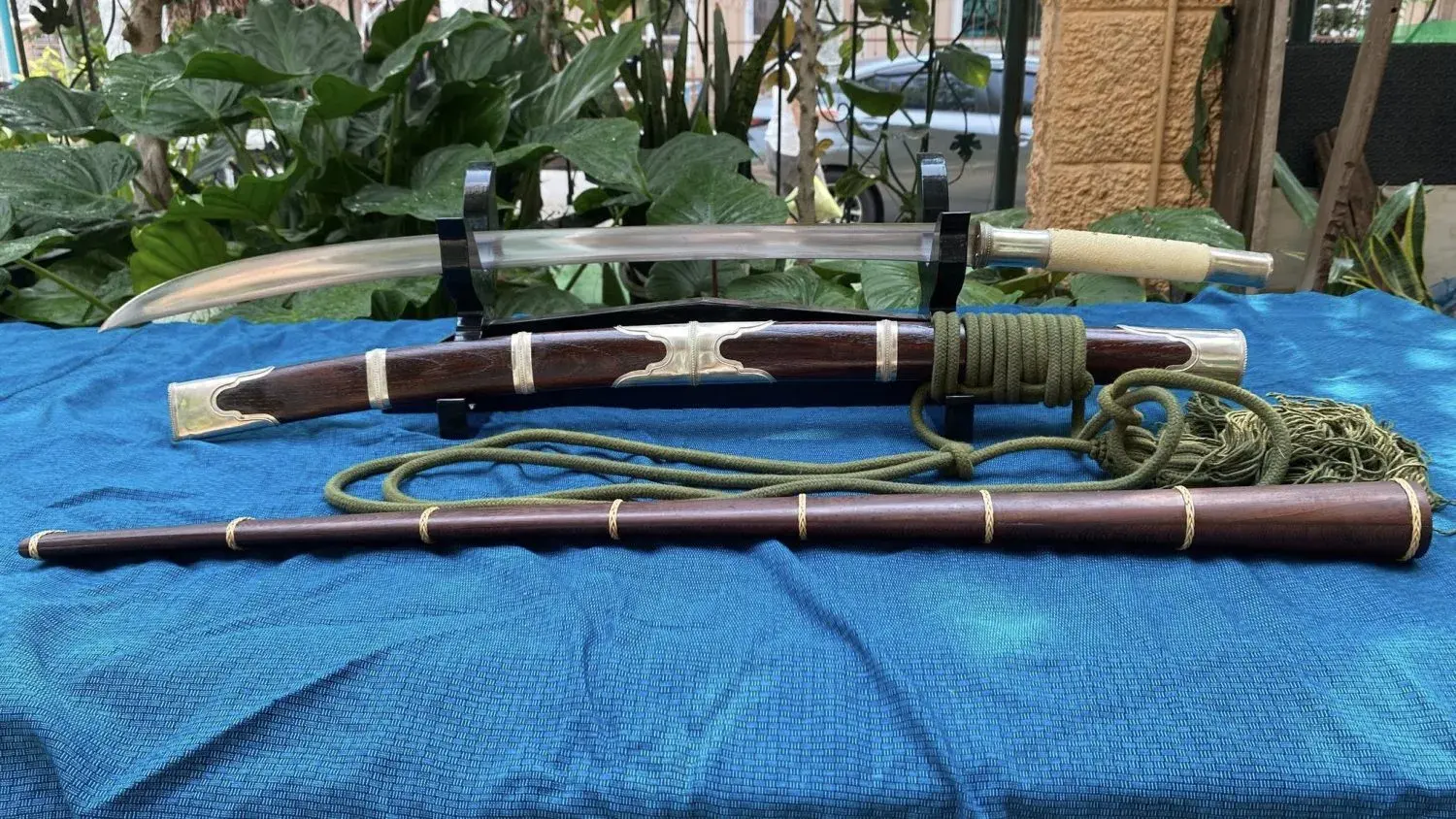 Custom build with white-metal fittings, a pale handle and a dark wood scabbard with metal bands, olive rope