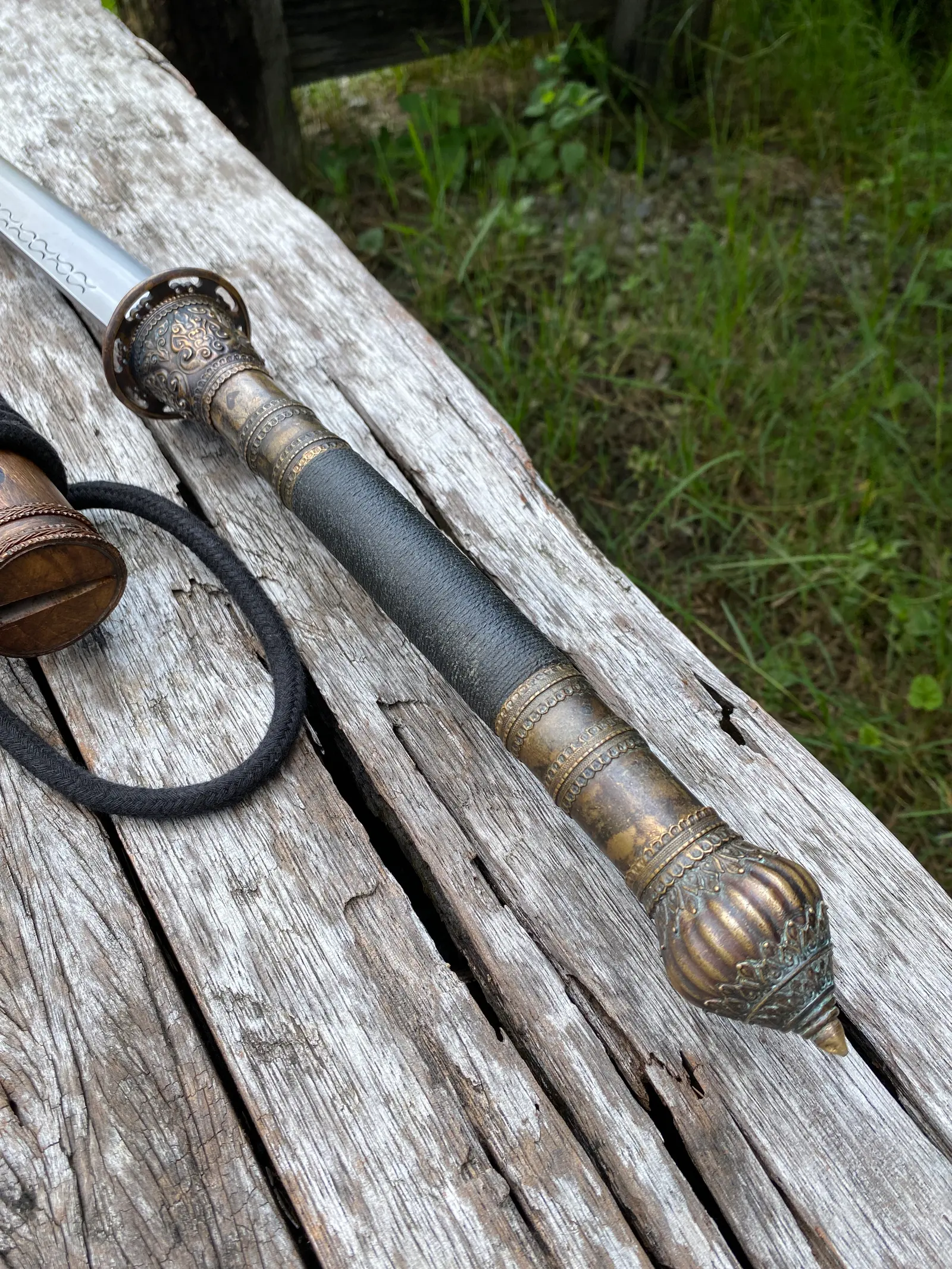 The handle: bronze guard, wrapped grip and lotus-bud pommel