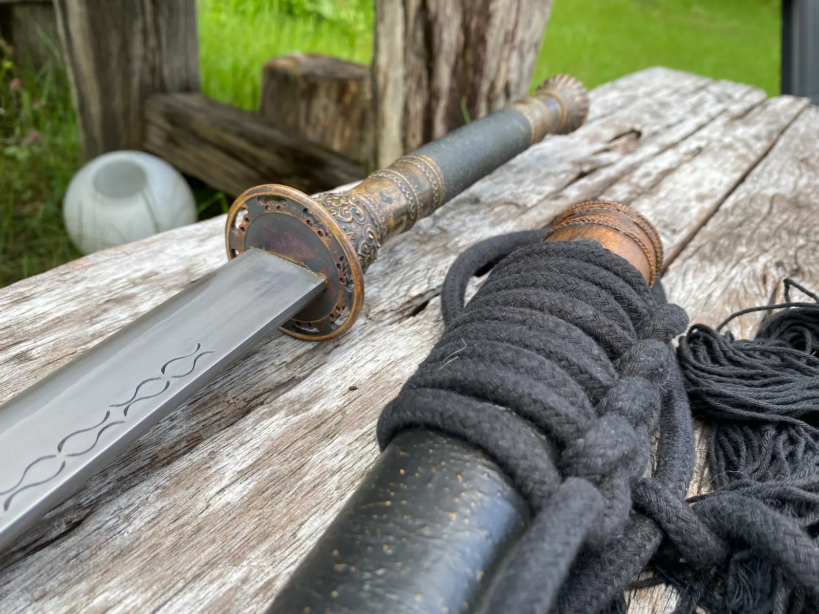 Blade root and guard showing the fuller and stamp chain, rope-wrapped scabbard behind