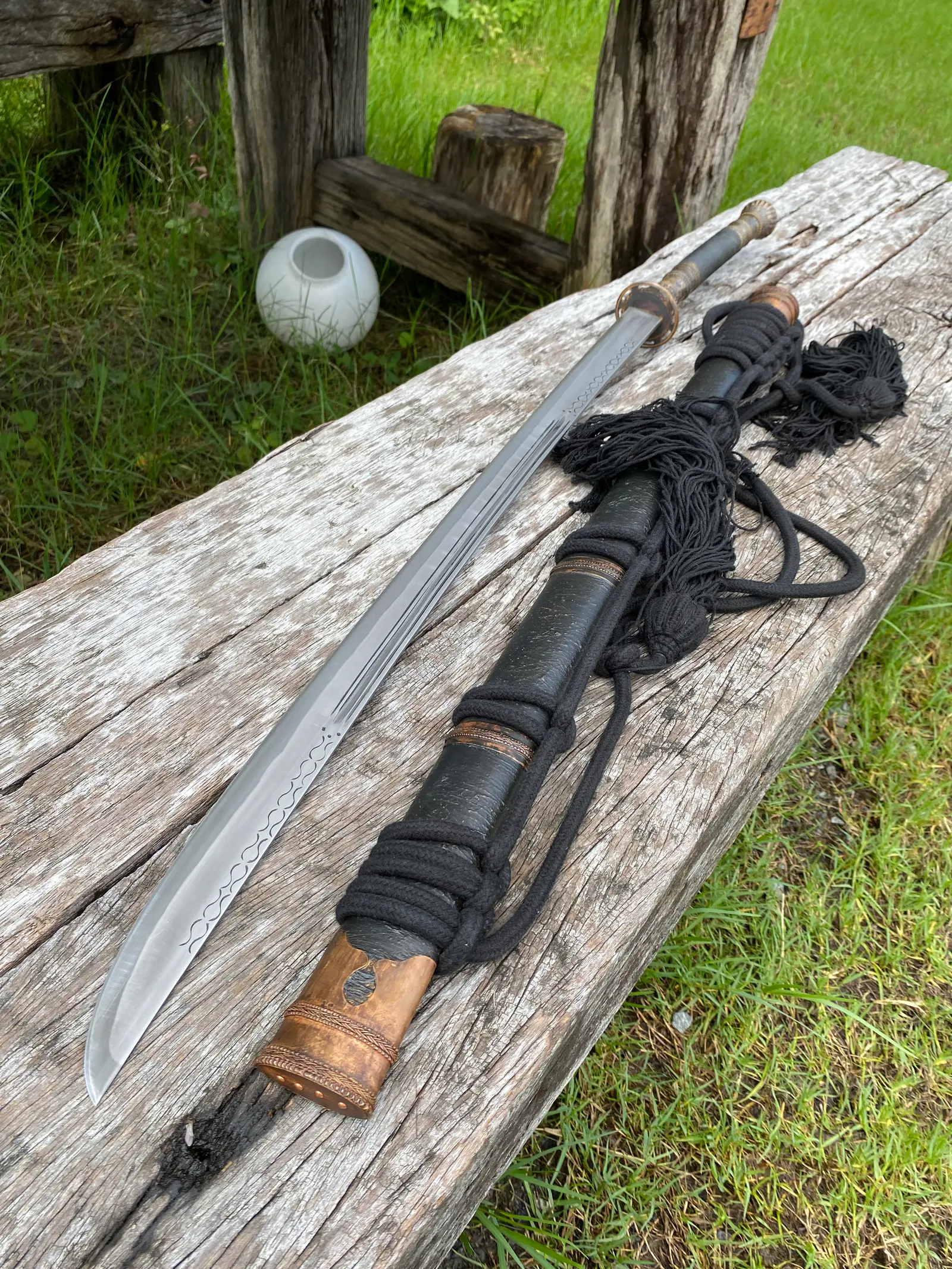 Curved blade and the copper toe sleeve of the scabbard on the plank