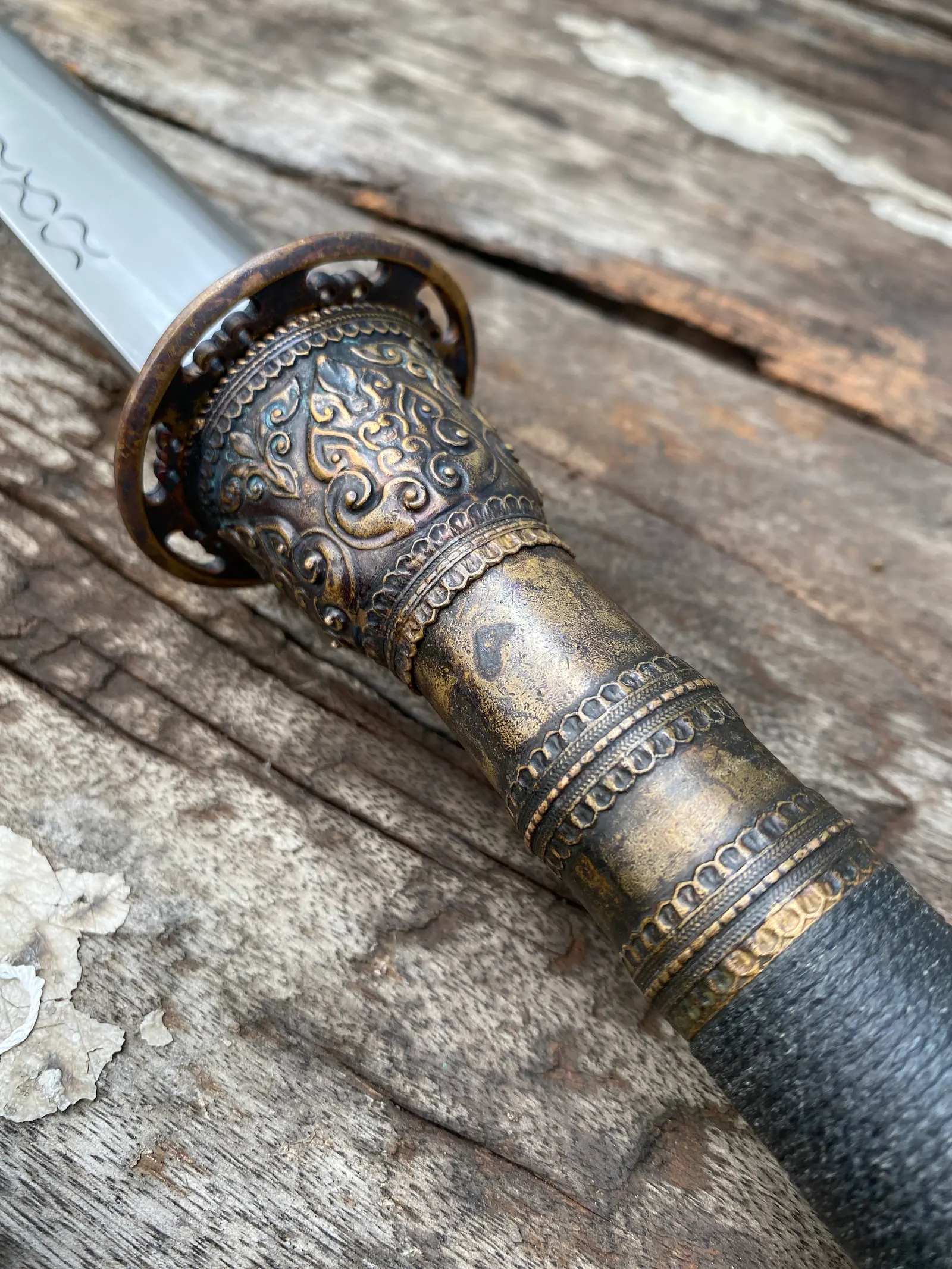 Close-up of the cast bronze guard and chased collar at the blade root