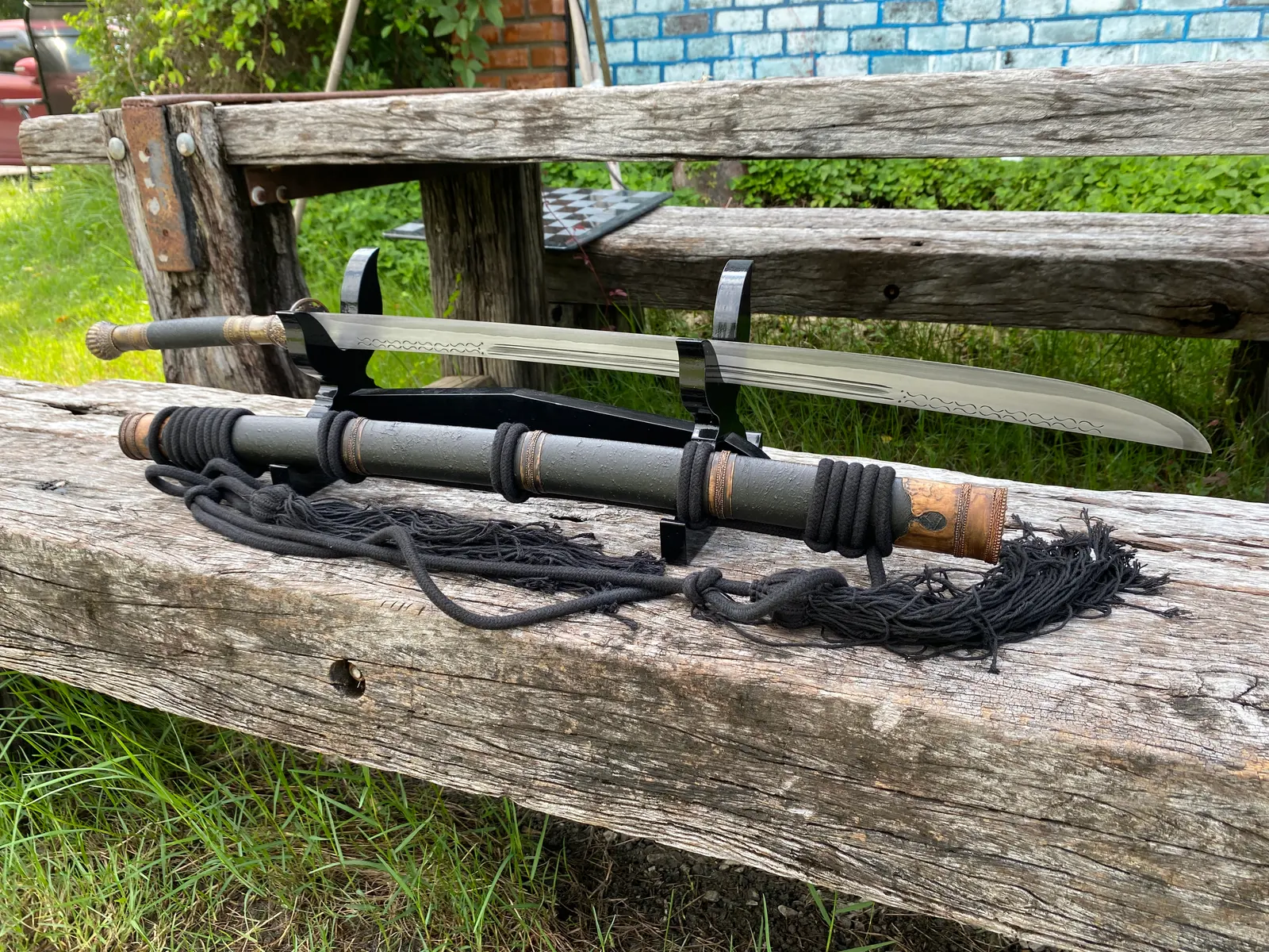 Sword on a black stand above its scabbard on a bench
