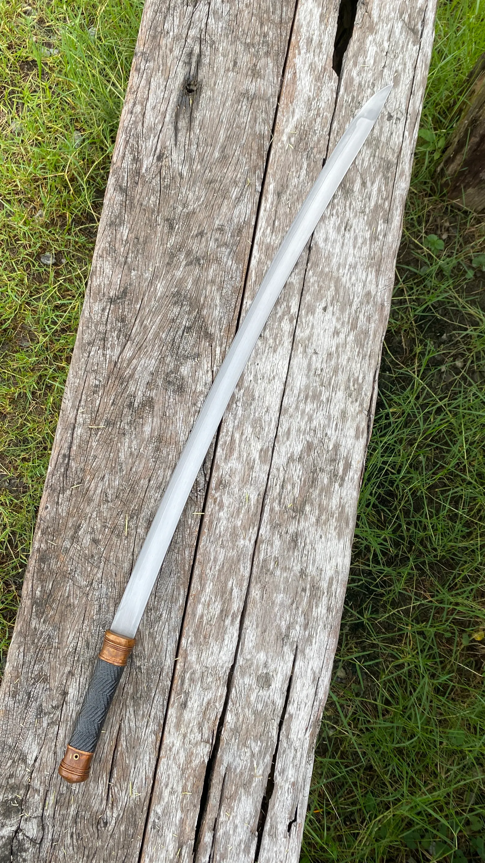 The drawn sword, full length, seen from the hilt end.