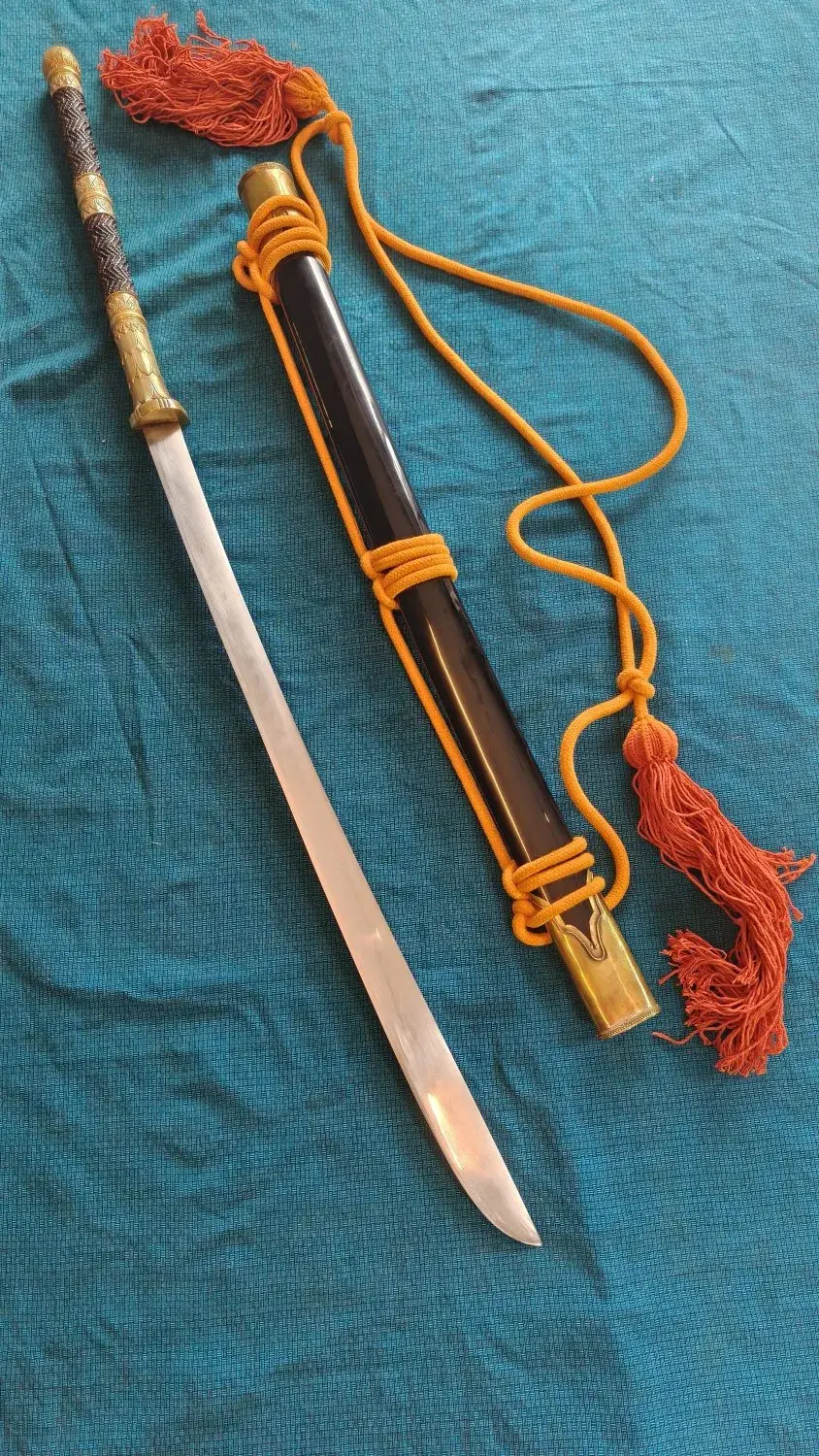 Overhead view of the full sword beside its black lacquer scabbard, with an orange carry cord and tassels.