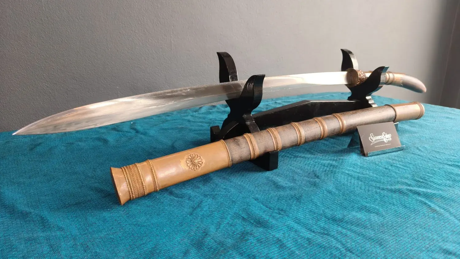 Three-quarter view from the point: ridged double-edged blade and the scabbard with its rosette sleeve.