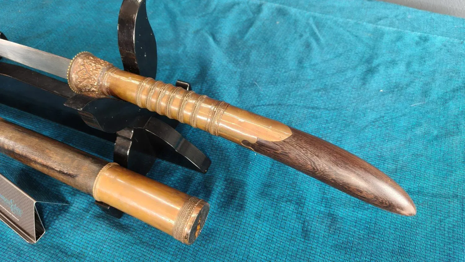 Close-up of the repoussé copper collar, ringed grip and pestle; the copper scabbard toe.