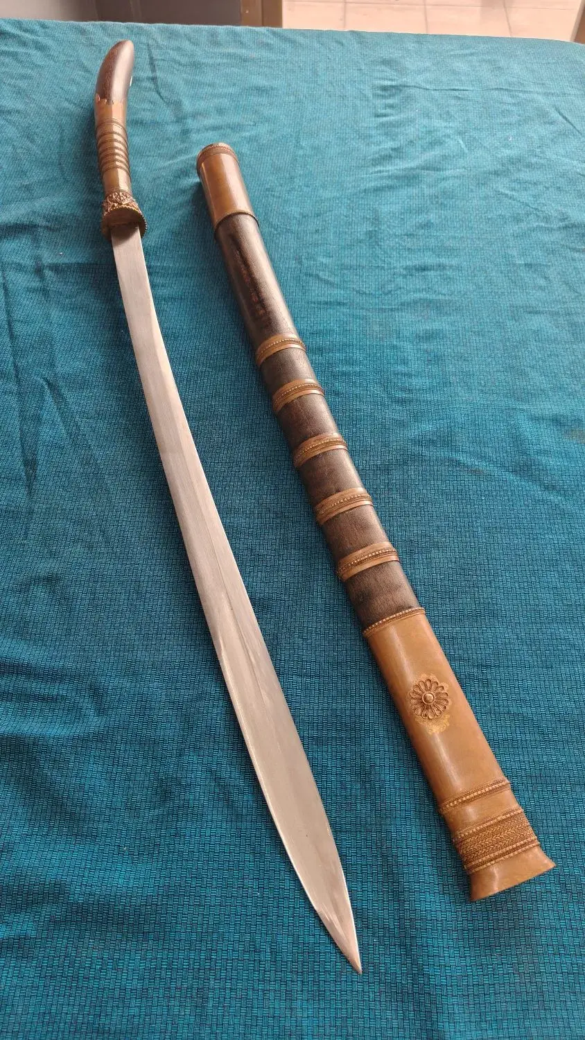 Tai Lue Dhaab from above: the drawn sword beside its scabbard, curved pestle handle at the top.