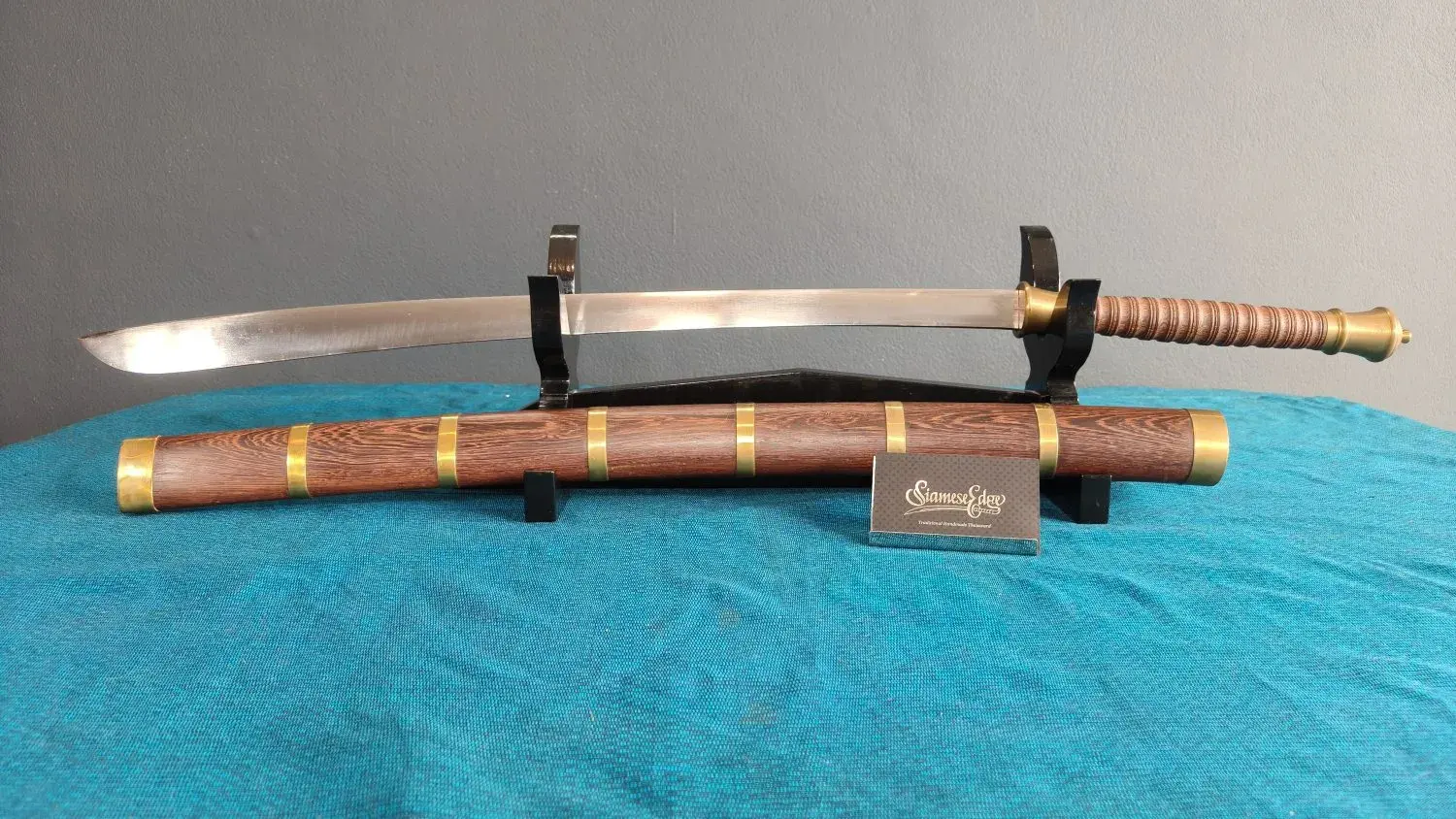 Side view of the Dhaab Dang on a black stand with its scabbard below