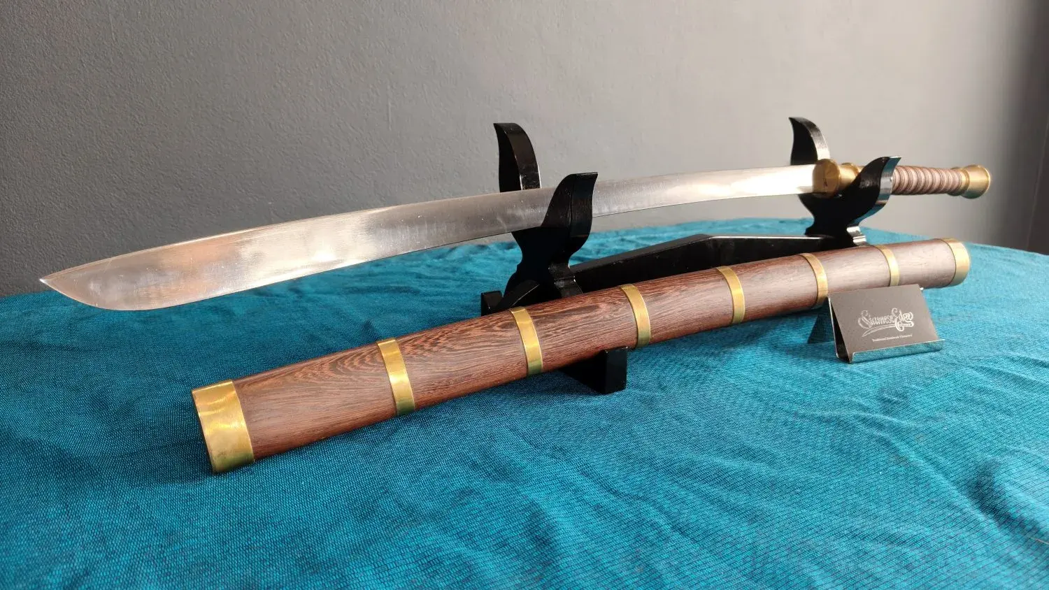 Three-quarter view from the tip: the broad blade over the banded scabbard