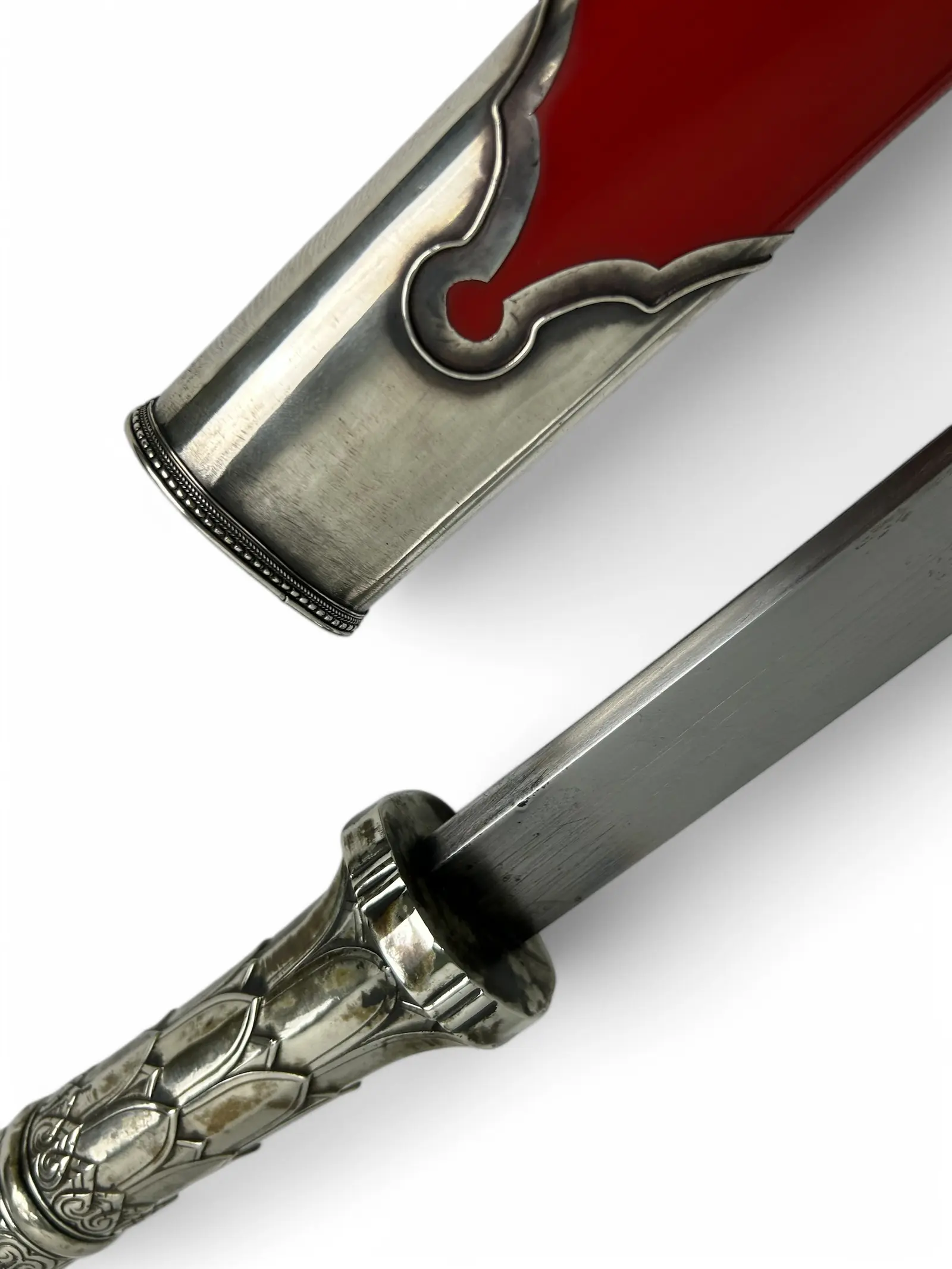Close-up of a silver chape and a lotus ferrule on a crimson-lacquer scabbard.