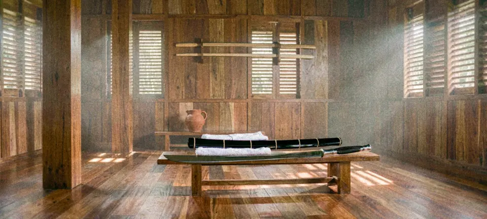 A teak training hall: a Thai dhaab and its scabbard on a low bench beside a clay jug and a folded cloth, their owner away on a break.
